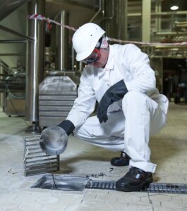 worker inspecting facility drain
