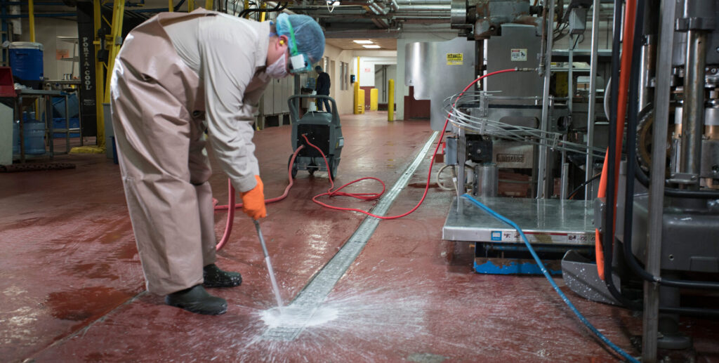 employee spraying drains with cleaning product